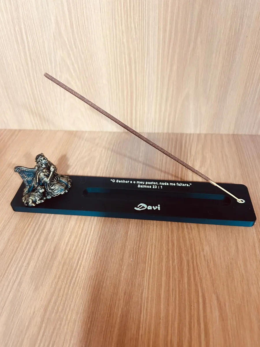 Incensário Davi: base preta com figura em bronze tocando harpa e um incenso aceso