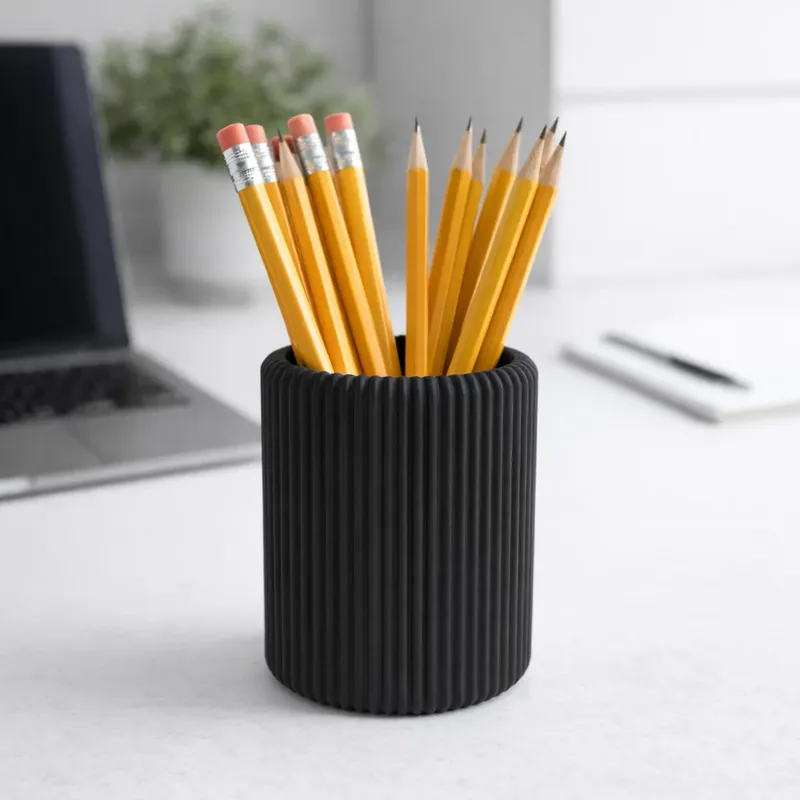 Porta-lápis preto canelado sobre uma mesa de trabalho, cheio de lápis